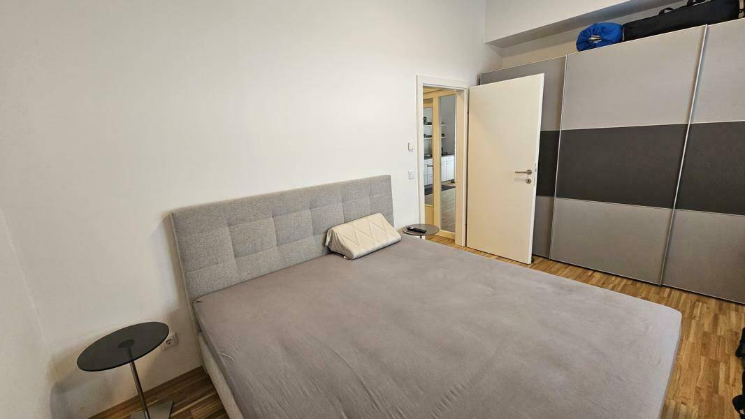 Helles Schlafzimmer mit modernem Bett, praktischem Kleiderschrank und Holzboden für Komfort.