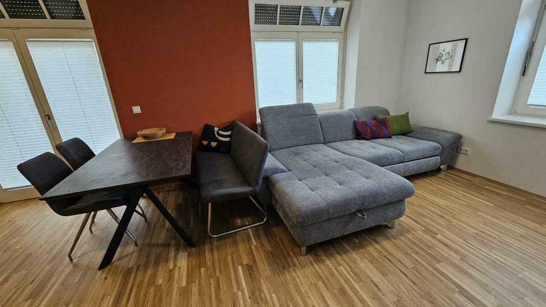 Moderner Wohn-Essbereich mit großem Ecksofa, Esstisch und hellem Holzfußboden.