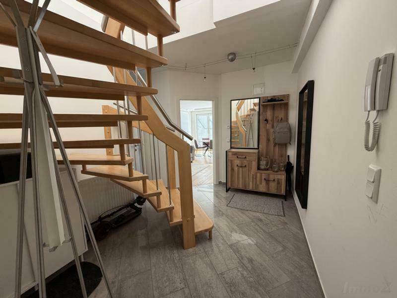 Heller Flur mit eleganter Holztreppe und modernen Fliesen, der die verschiedenen Ebenen des Hauses verbindet.