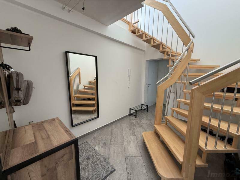 Geräumiger Flur mit offener Holztreppe und großem Spiegel, der den Raum optisch erweitert und viel Licht reflektiert.