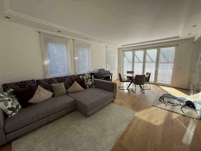 Lichtdurchfluteter Wohn-Essbereich mit großem Sofa, Esstisch und hellem Parkettboden, ideal für gesellige Abende.