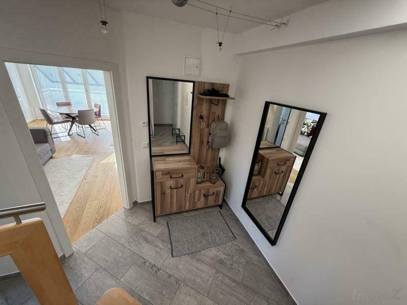 Eingangsbereich mit moderner Garderobe und Holztreppe, die zu den oberen Etagen führt, hell und einladend gestaltet.