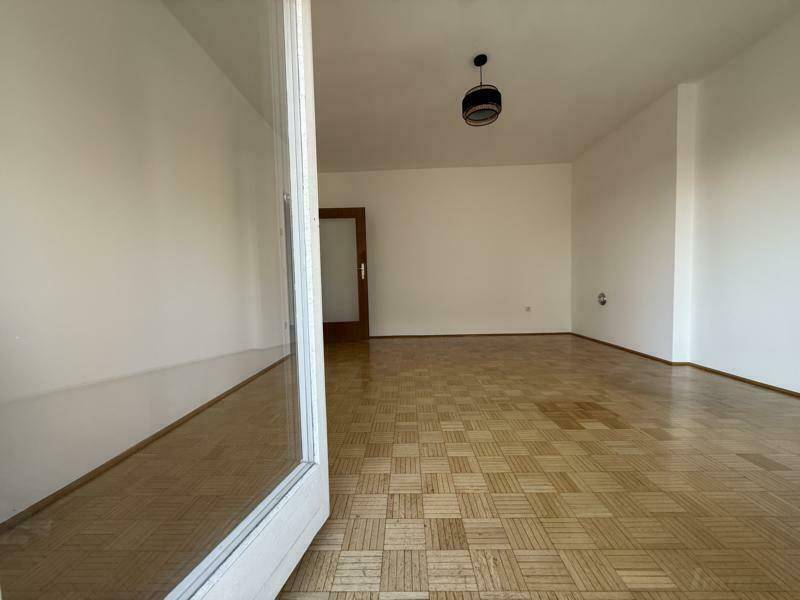 Leeres Wohnzimmer mit Parkettboden und Blick auf die Innentür.