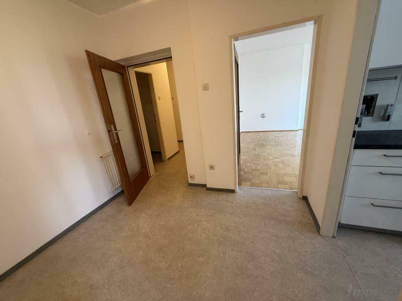 Flur mit hellem Boden und Türen zu angrenzenden Räumen.