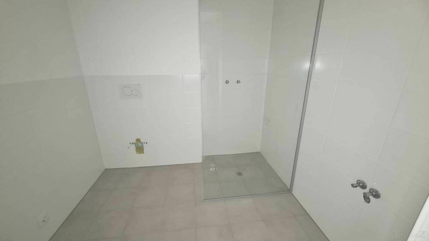Unmöbliertes Badezimmer mit begehbarer Dusche und Wand-WC-Vorbereitung, bereit für den Ausbau.