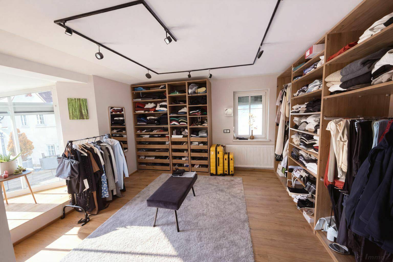 Geräumiger begehbarer Kleiderschrank mit umfangreichen Regalsystemen und Sitzbank.