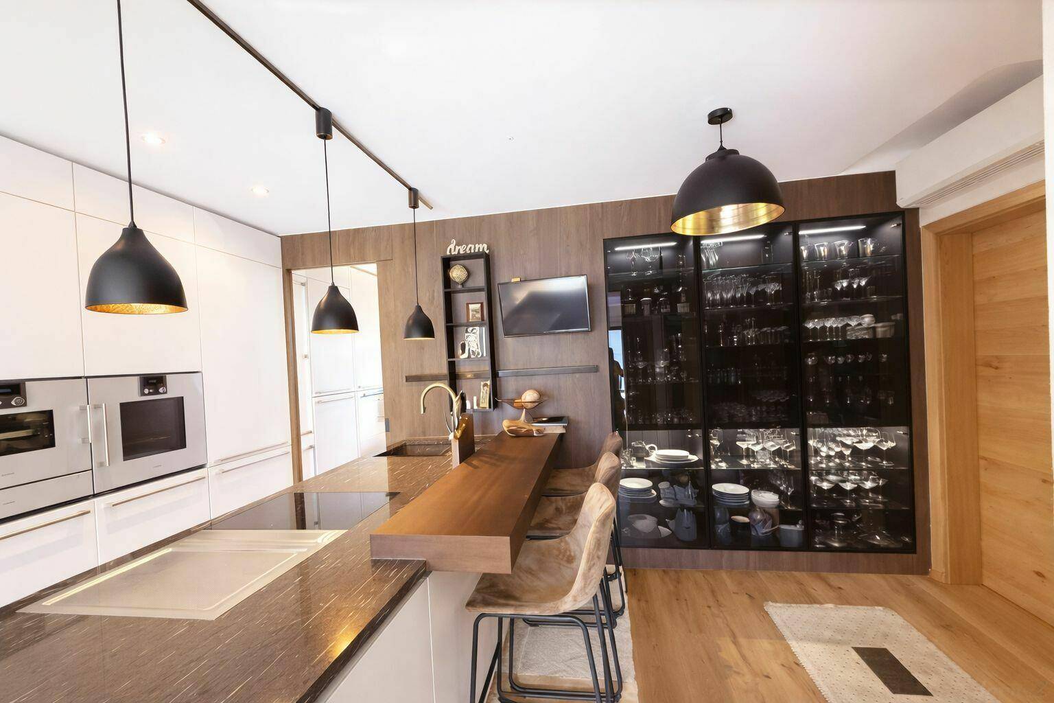 Moderne Küche mit weißen Fronten, dunkler Arbeitsplatte und integriertem Weinkühlschrank.