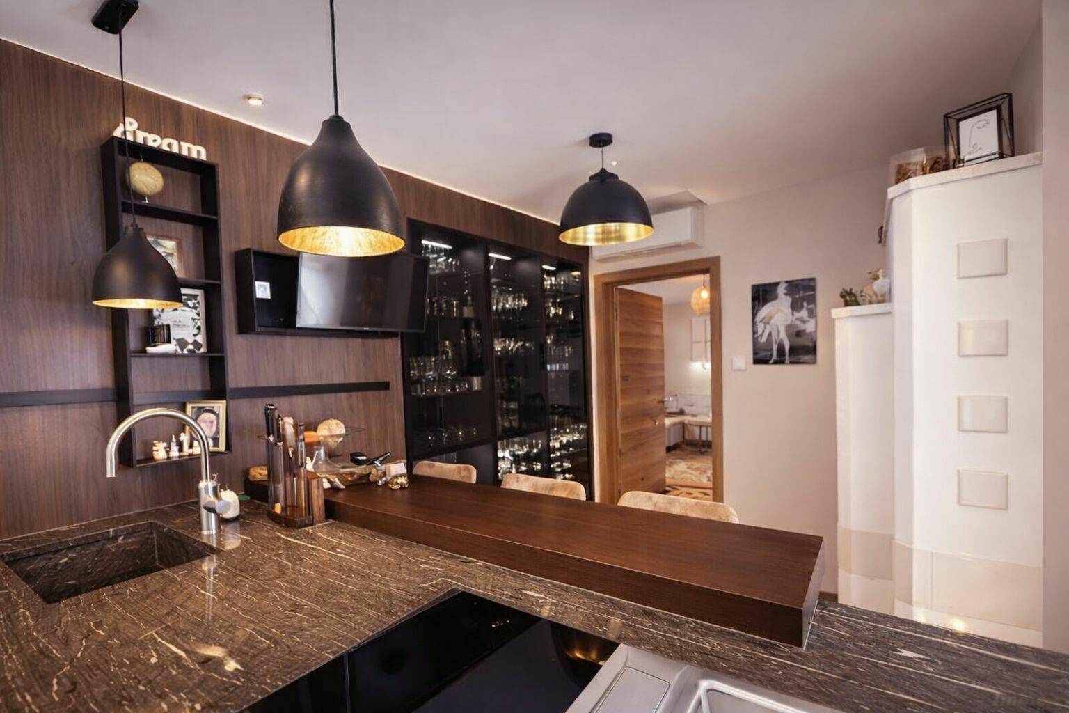 Elegante Küche mit dunklen Granitarbeitsplatten, integrierter Bar und Weinschrank.