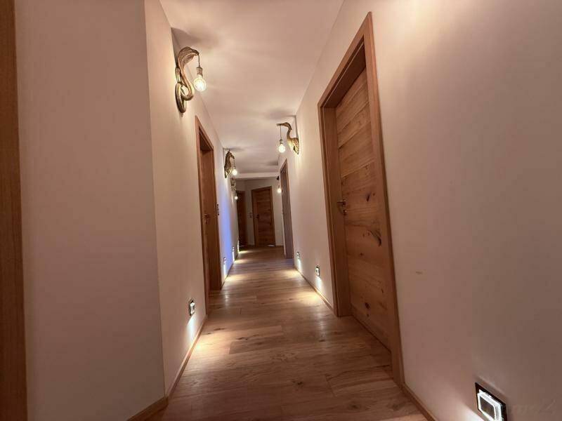 Heller Flur mit Holzboden, mehreren Türen und indirekter Beleuchtung.