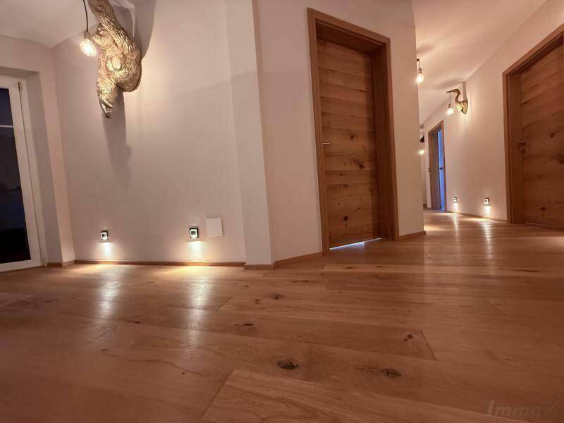 Langer Flur mit Holzboden, Holztüren und integrierter Bodenbeleuchtung.