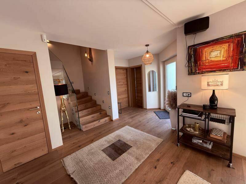 Moderner Eingangsbereich mit Holzboden, Treppe und stilvoller Beleuchtung.