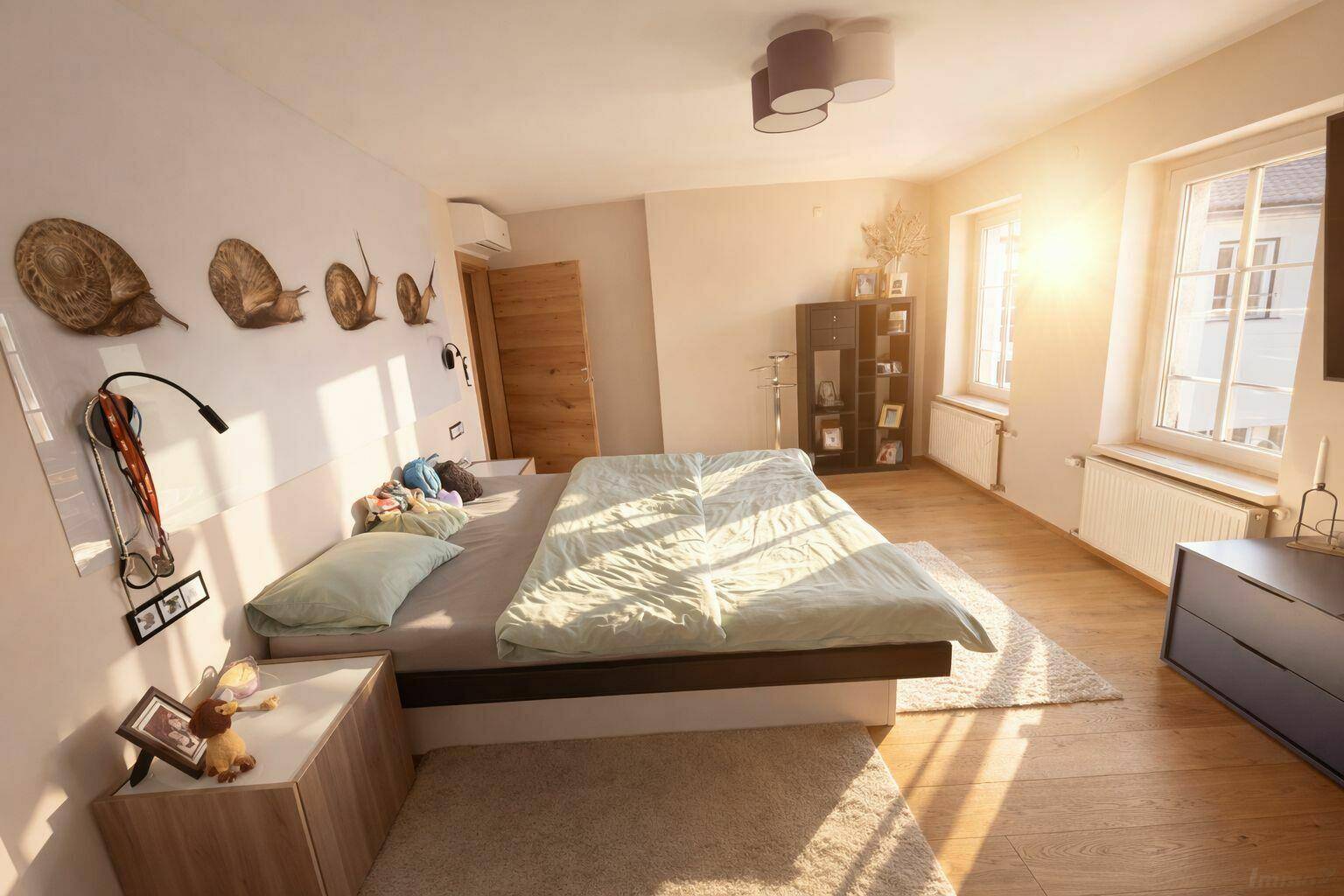 Helles Schlafzimmer mit Holzboden, Doppelbett und Fenster mit viel Tageslicht.
