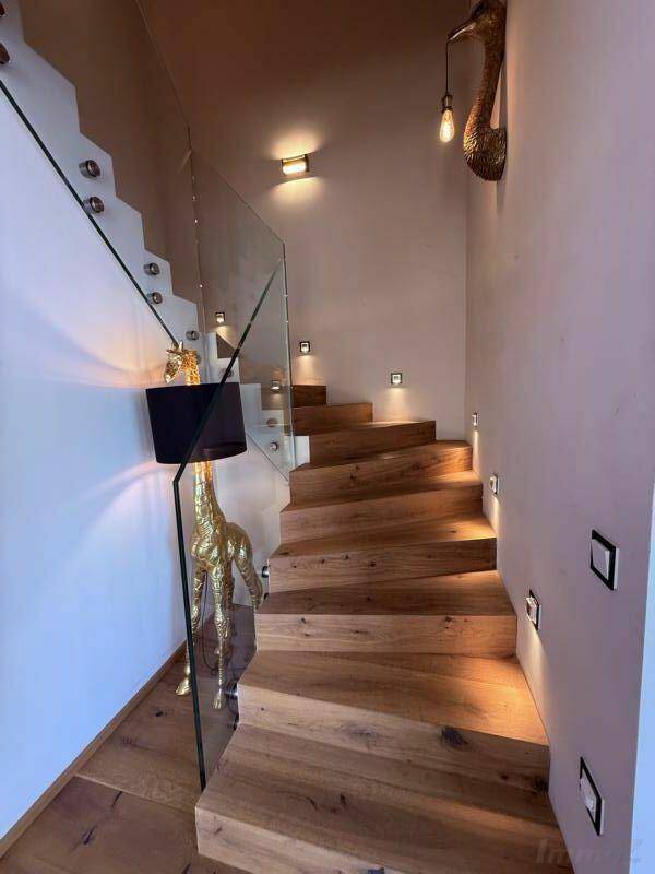 Elegante Holztreppe mit Glasgeländer und integrierter Wandbeleuchtung.