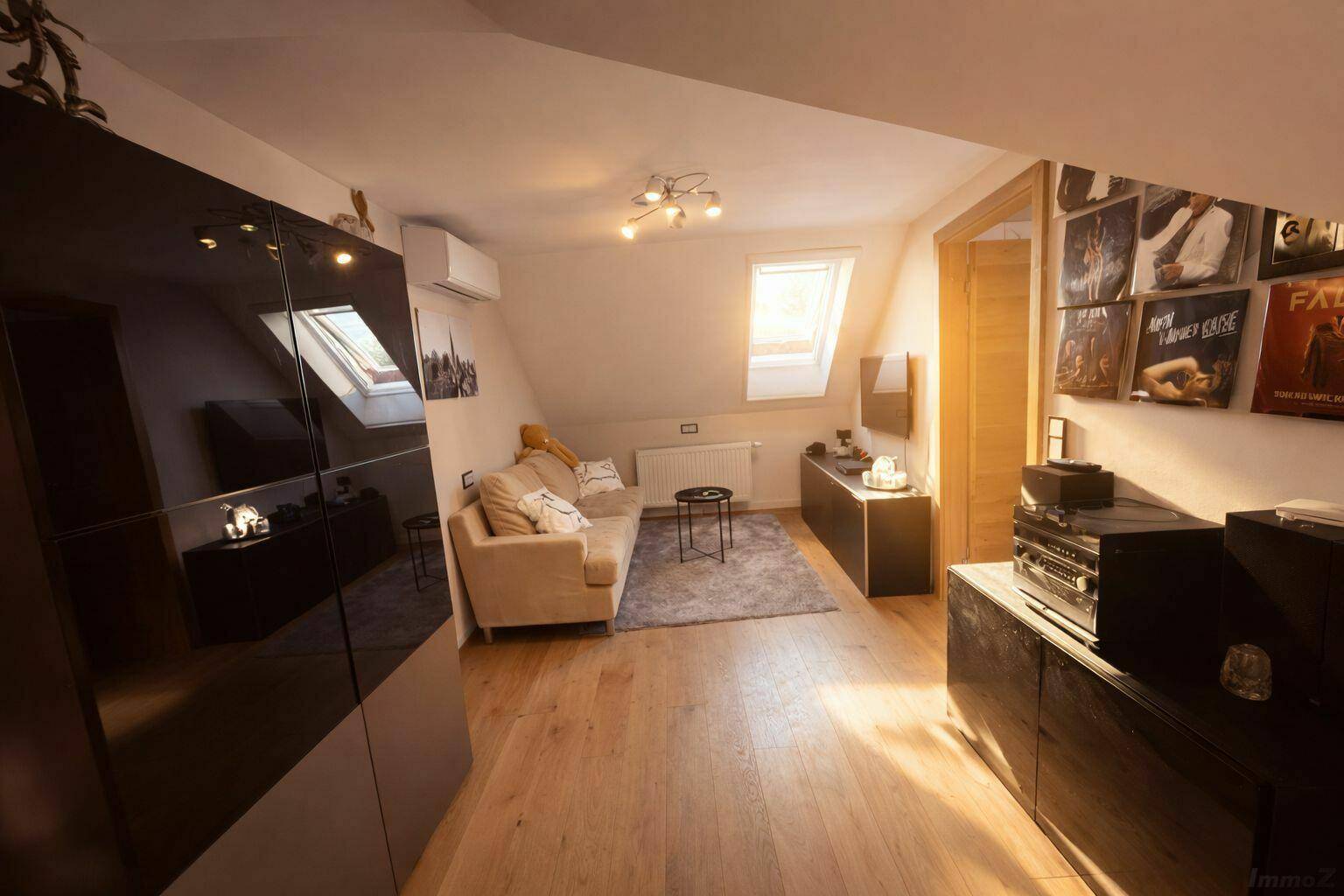 Gemütliches Wohnzimmer im Dachgeschoss mit Schrägdach, Sofa und Holzboden.