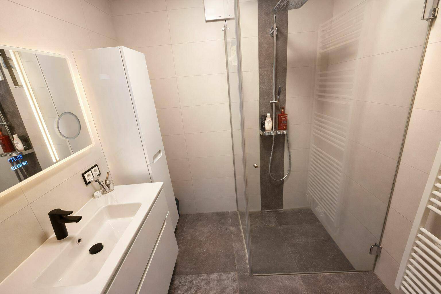 Modernes Badezimmer mit ebenerdiger Dusche, Waschtisch und weißem Schrank.