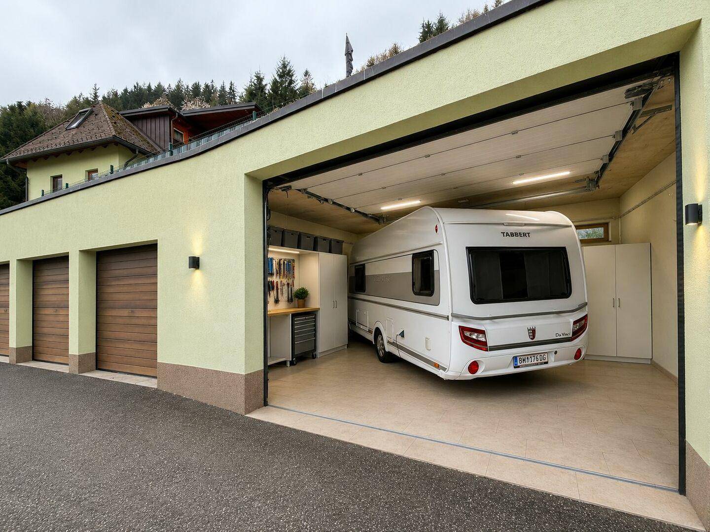Geräumige Garage mit mehreren Stellplätzen, einem Wohnwagen und integrierten Schränken.