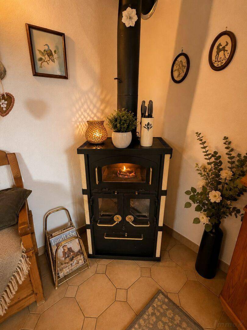 Gemütliche Ecke mit Holzofen, Fliesenboden und traditionellen Wanddekorationen.
