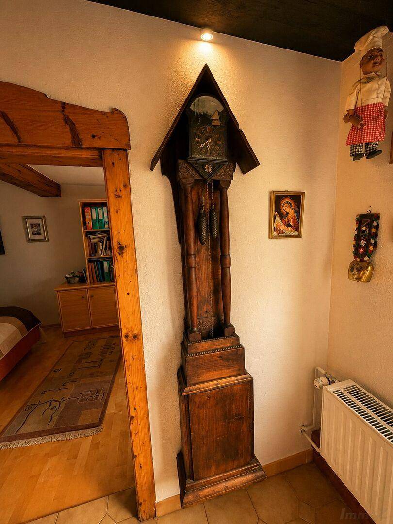 Rustikaler Flur mit Standuhr, Holzelementen und traditioneller Dekoration.