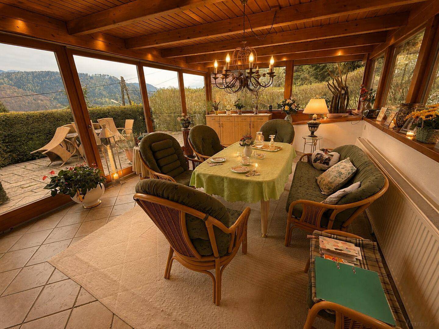 Heller Wintergarten mit Holzbalkendecke, Essbereich und weitem Blick in die Natur.