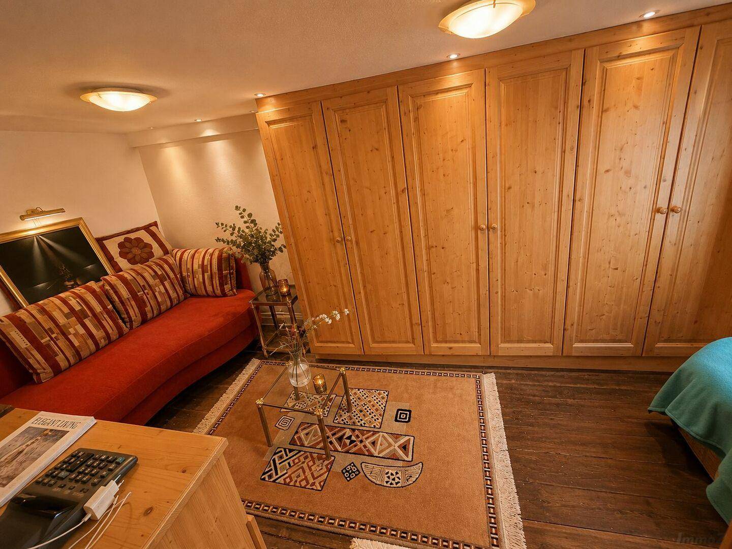 Gemütliches Schlafzimmer mit Einbauschränken, Sofa und Holzboden unter Dachschrägen.