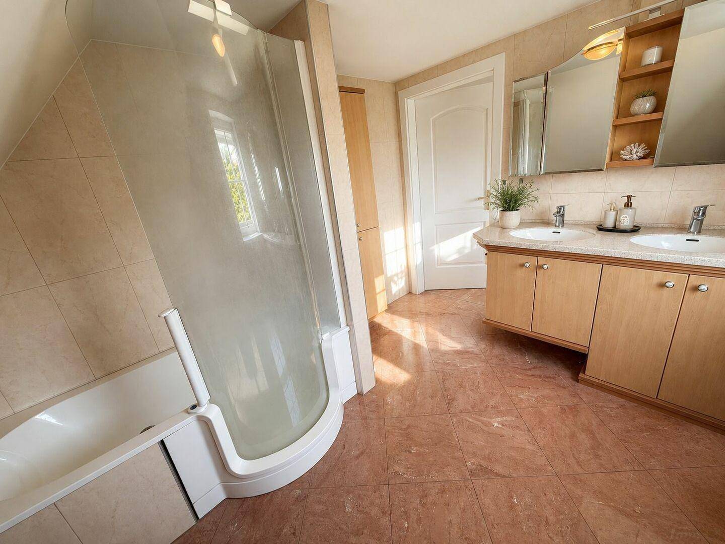 Badezimmer mit Badewanne, Duschkabine und Doppelwaschbecken.