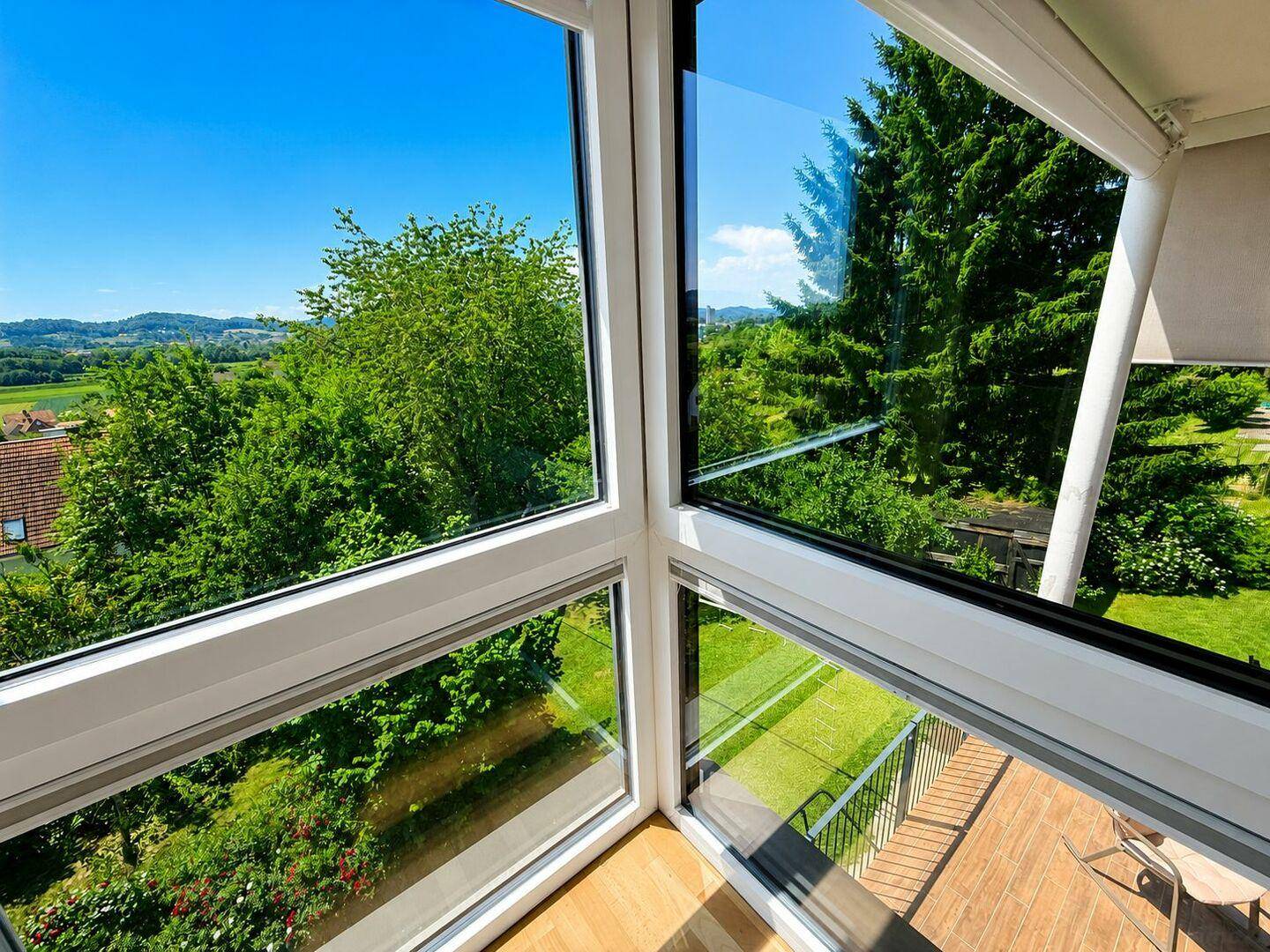 Weitläufiger Ausblick aus großen Fenstern auf die grüne Landschaft und die Terrasse.