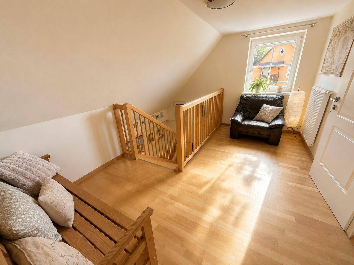 Gemütlicher Dachgeschossflur mit Holzboden und einem Fenster, das viel Licht hereinlässt.
