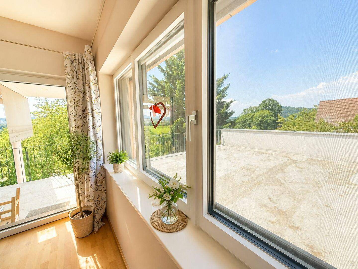 Große Fensterfront mit Blick auf die Terrasse und die grüne Umgebung.