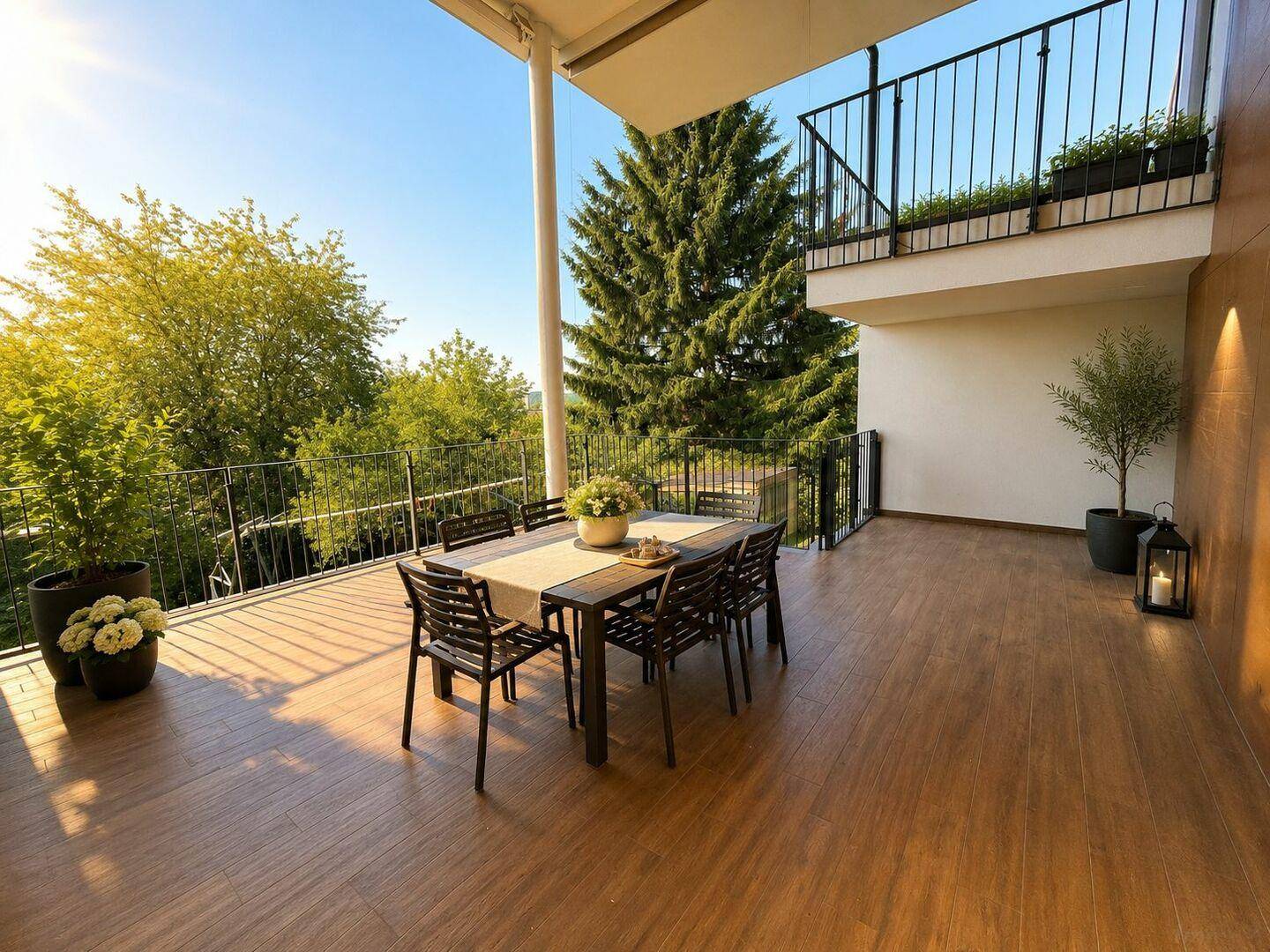 Sonniger Terrassenbereich mit Esstisch, umgeben von Bäumen und viel Grün.