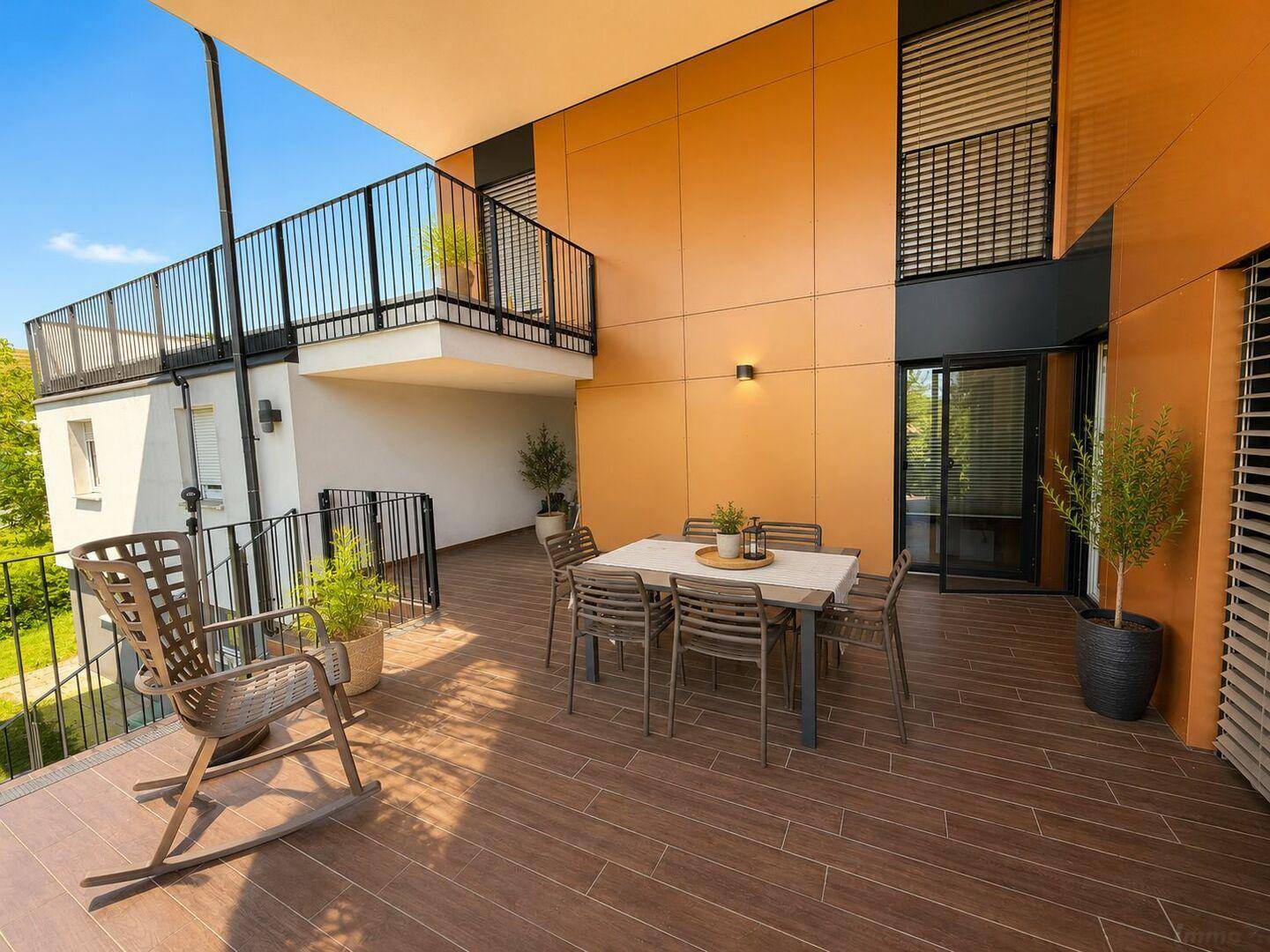Geräumige Terrasse mit Essbereich und Schaukelstuhl, ideal für entspannte Stunden im Freien.