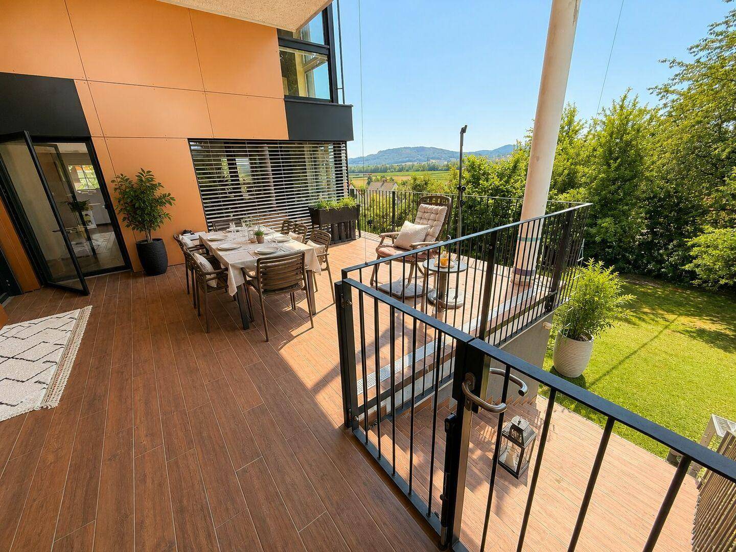 Große Terrasse mit Essbereich und weitem Blick über die grüne Landschaft und Berge.