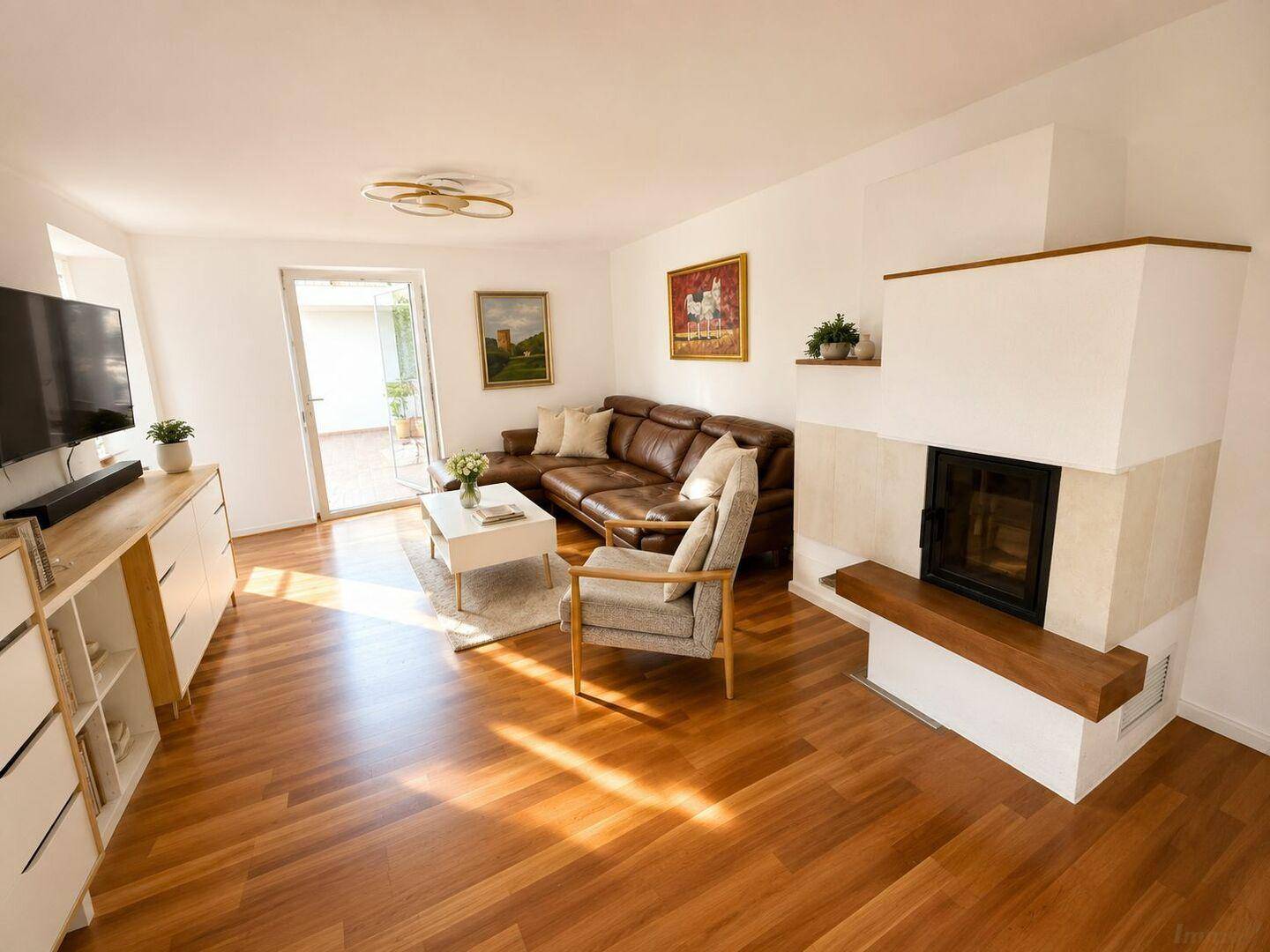 Gemütliches Wohnzimmer mit Kamin, Ledersofa und Zugang zu einem sonnigen Außenbereich.
