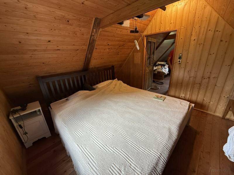 Schlafzimmer im Dachgeschoss mit Holzwänden, schrägen Decken und Doppelbett, einladende Atmosphäre.
