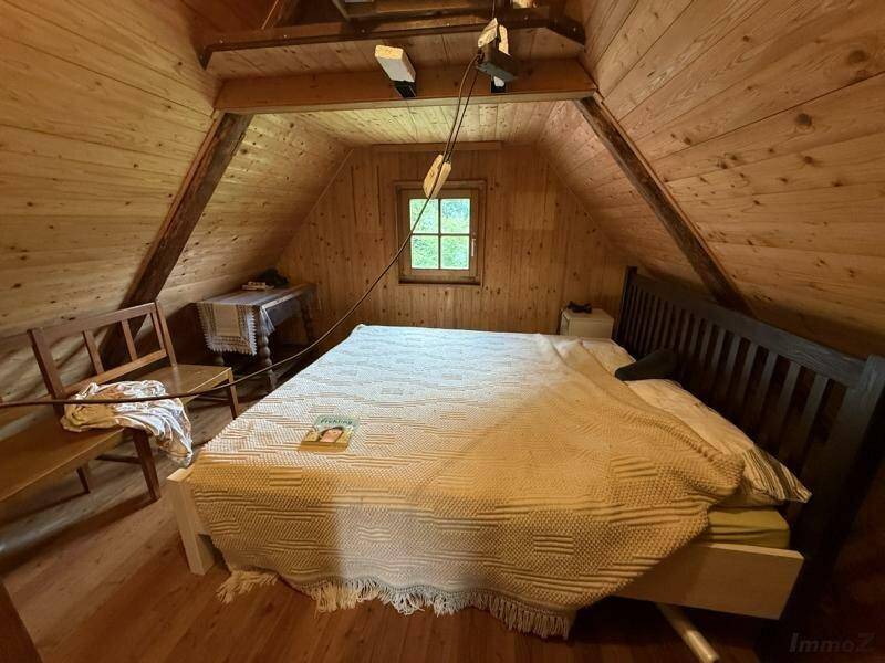 Helles Schlafzimmer im Dachgeschoss mit Holzwänden und schrägen Decken, viel natürliches Licht.