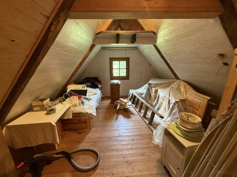 Dachgeschossraum mit Holzboden, schrägen Wänden und einfacher Einrichtung, vielseitig nutzbar.