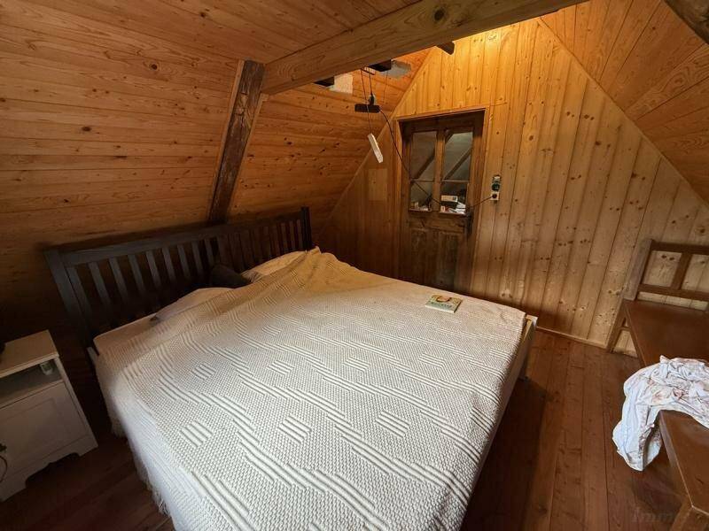 Gemütliches Schlafzimmer im Dachgeschoss mit Holzwänden und Doppelbett, rustikaler Charme.