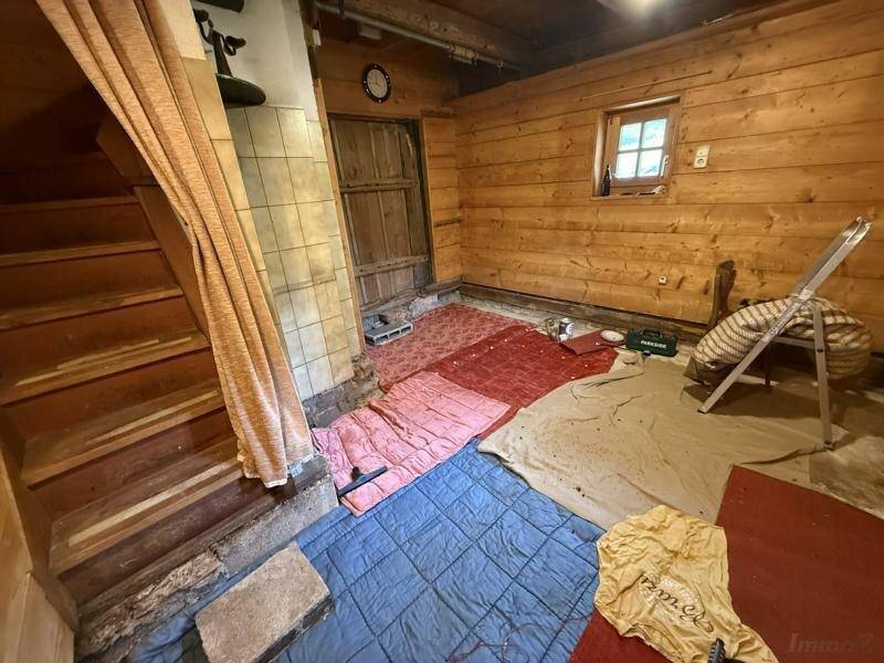 Innenraum mit Holzverkleidung, Treppe und verschiedenen Abdeckungen auf dem Boden, rustikales Ambiente.
