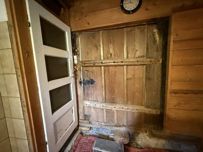 Eingangsbereich zu einem rustikalen Holzraum mit alter Holztür, voller Charakter und Geschichte.