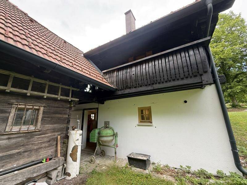 Rustikale Hausfassade mit Holzelementen und Ziegeldach in ländlicher Umgebung, charmantes Erscheinungsbild.