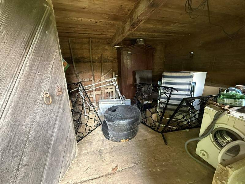 Abstellraum mit Holzdecke, alten Möbeln und einer Waschmaschine, bietet viel Stauraum.