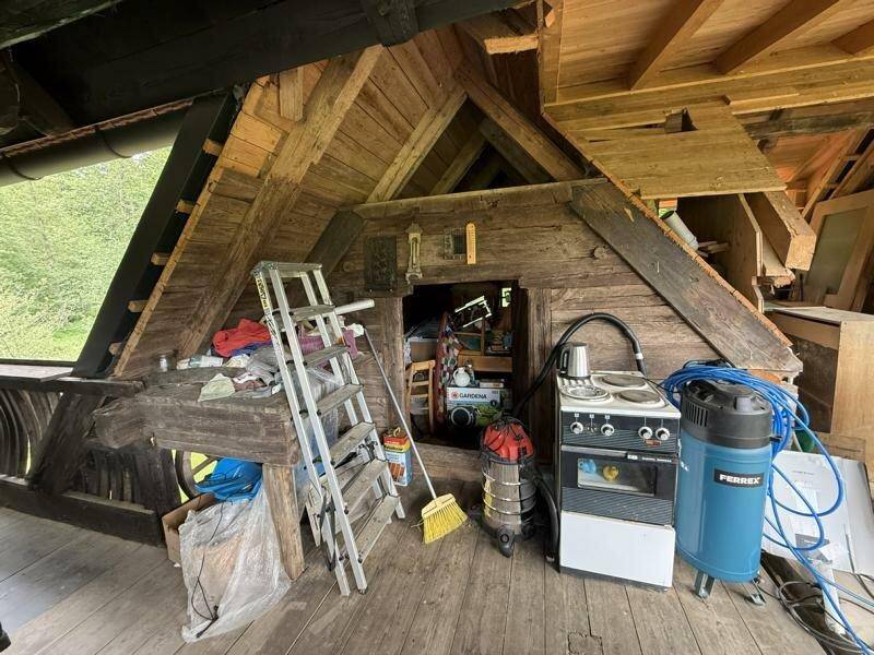 Dachgeschossbereich mit Holzverkleidung, Leiter und verschiedenen Geräten, ideal als Lagerraum.