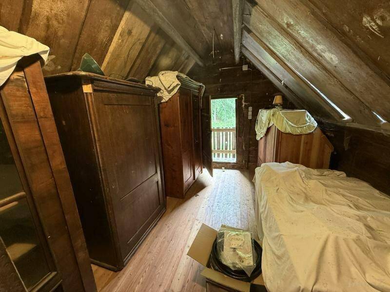 Dachgeschosszimmer mit Holzbalken, schrägen Wänden und einfacher Einrichtung, bietet viel Potenzial.