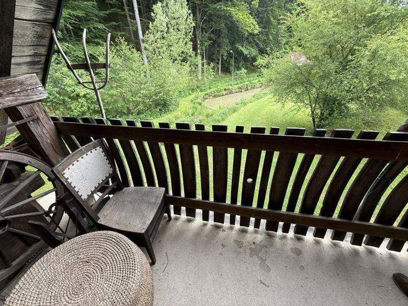 Rustikaler Holzbalkon mit Sitzgelegenheiten und weitem Blick ins Grüne, umgeben von Natur.