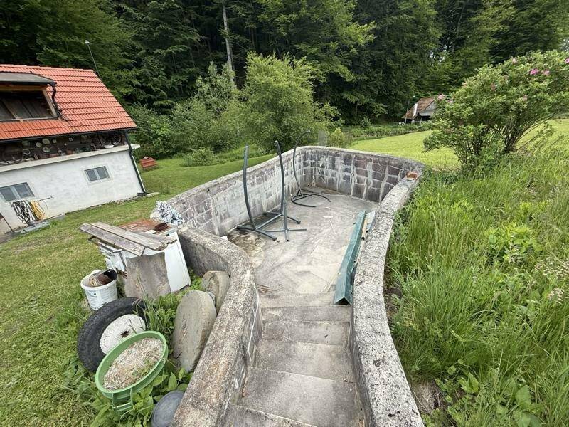 Unfertiger Poolbereich im Garten mit Blick auf die umliegende Natur und Waldlandschaft.