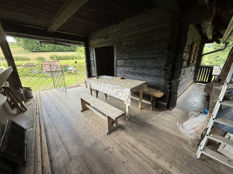Überdachte Holzterrasse mit rustikalen Möbeln und Blick ins Grüne, ideal für entspannte Stunden.