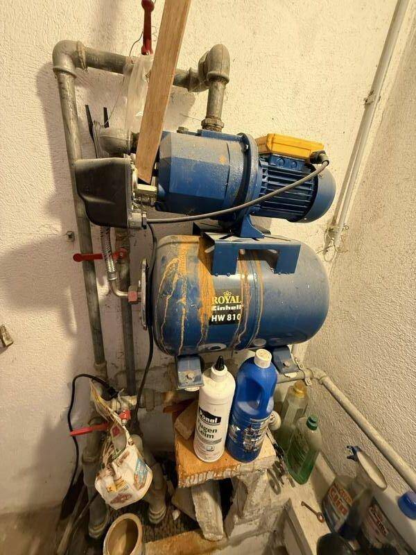 Hauswirtschaftsraum mit Wasserpumpe und sichtbaren Rohrleitungen, funktional und praktisch.