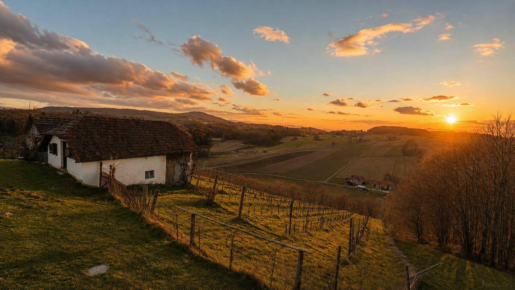 Ländliches Haus in einer Weinregion bei Sonnenuntergang mit weitem Blick über die Landschaft.