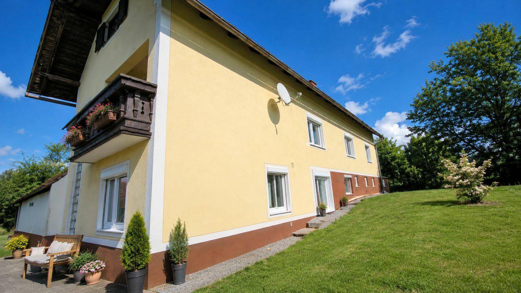 Seitenansicht des Hauses mit großem Rasenbereich und Blick auf die grüne Umgebung.