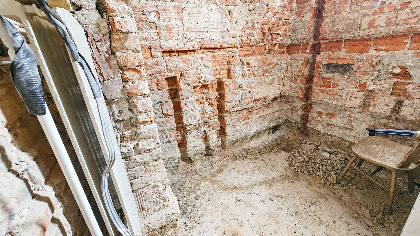 Unfertiger Kellerraum mit freiliegenden Ziegelwänden und Erdboden, bereit für den Ausbau oder die Renovierung.