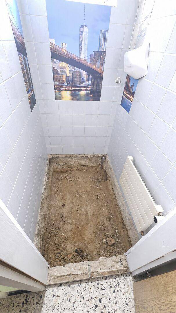 Kleiner gefliester Raum mit ausgehobenem Boden, wahrscheinlich für die Installation eines Badezimmers oder WCs.